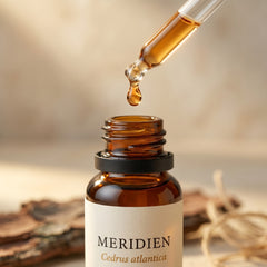MERIDIEN essential oil dropper close-up — single amber drop